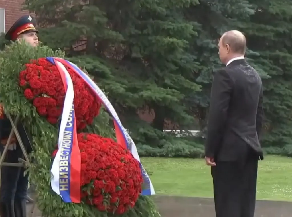 Vladimir Putin standing in heavy rain to honor WWII victims